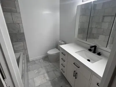 Bathroom with white vanity, toilet, and marble floor