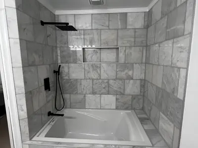 Marble tiled tub surround with niche and shower