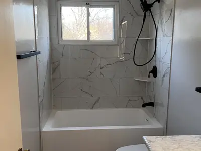 Marble tub-shower with window and black fixtures