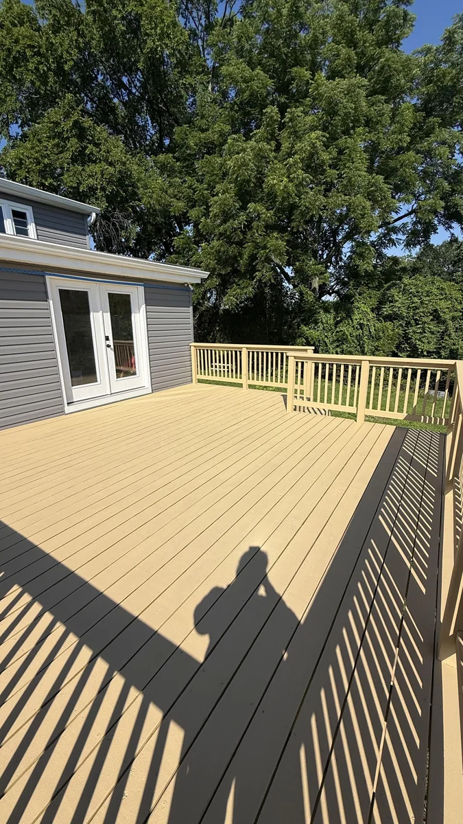 Finished tan composite deck with railings behind a remodeled home