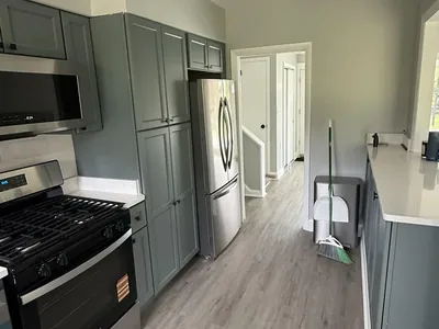 Remodeled galley kitchen with sage green cabinets and stainless gas range