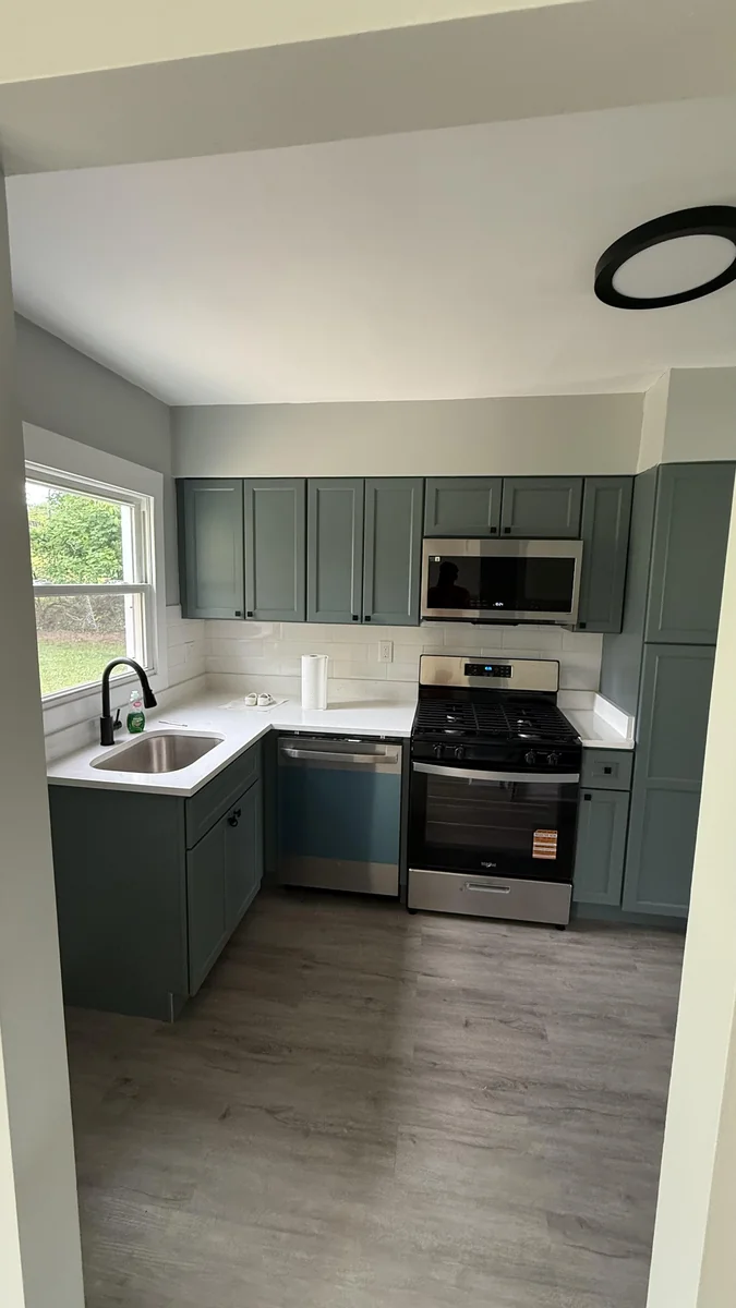 Sage green kitchen remodel with white quartz counters and subway tile backsplash
