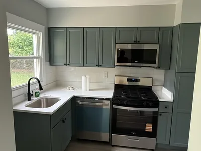 Sage green kitchen remodel with white quartz counters and subway tile backsplash