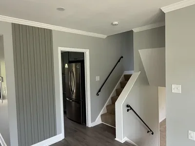 Interior remodel with fresh paint, board-and-batten accent wall, and refinished staircase